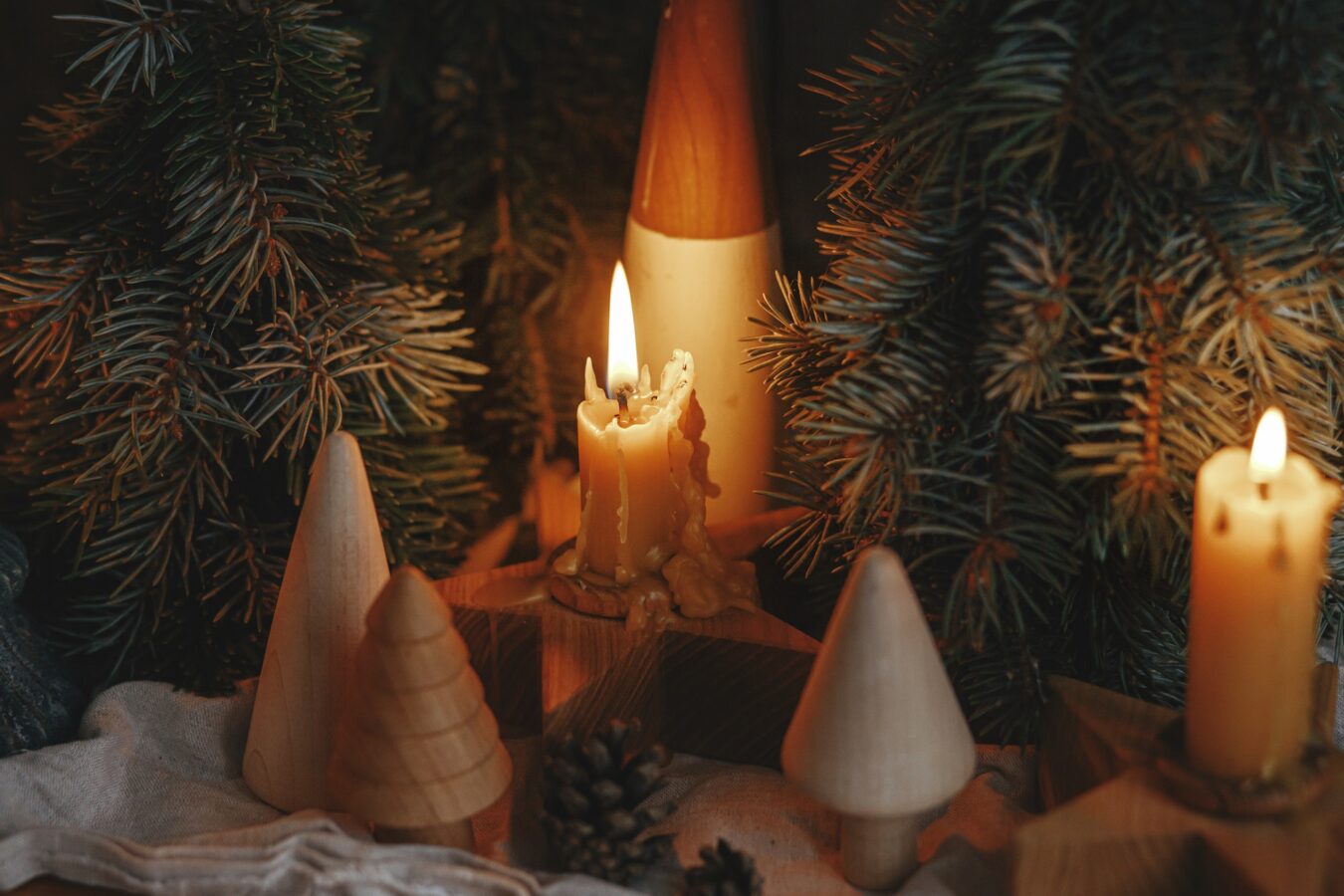 Stylish burning christmas candles, pine trees, cones decor on rustic background in evening